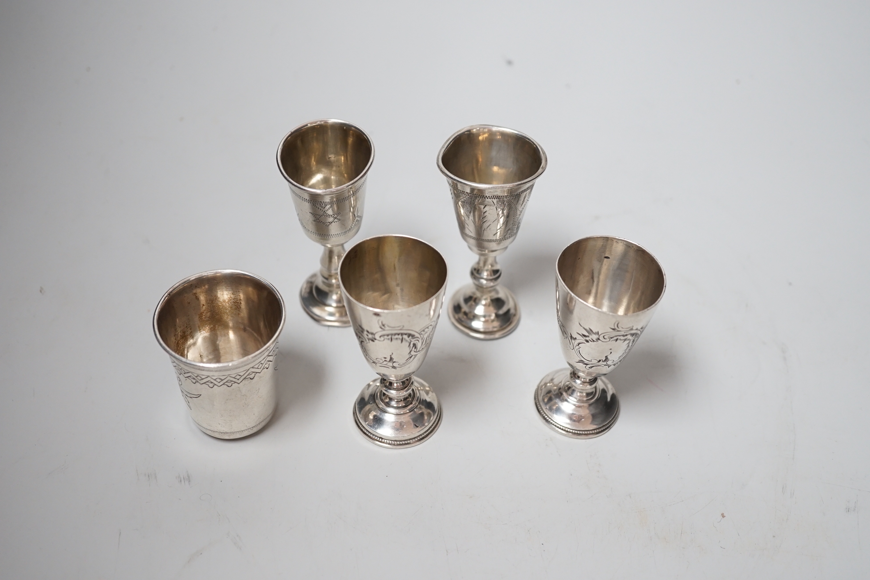 Two George V silver kiddush cups, 82mm, two Russian 84 zolotnik white metal pedestal tots and similar beaker, dated 1890, 4.6oz.